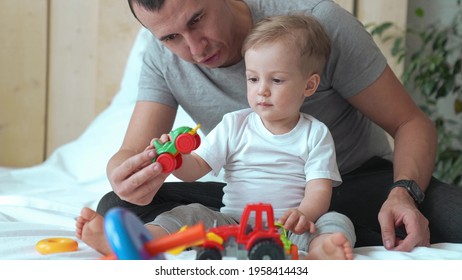 happy family at a home. dad and son play toy car and tractor. happy family at home together concept. son and father sitting on the bed in the bedroom playing toys car. dad and child play car fun toy