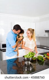 Happy Family In Home Kitchen Cooking Food