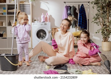 Happy Family At Home. Mother And Daughters Clean The House. Young Woman And Children Vacuum Sweep Mop Floor And Cleaners. Cute Little Helpers.