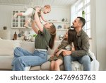 Happy family at home. Mother father two children daughters relaxing on sofa indoor. Mom dad parents baby girls kids relax playing having fun together. Family smiling laughing enjoying tender moment