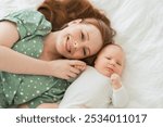 Happy family at home. Mother playing with little toddler child on bed. Mom baby relax playing having fun together. Mother looks at camera with love care. Mom of breast feeding baby rest in living room