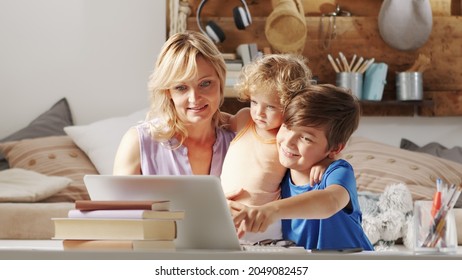 Happy Family At Home, Mother With Son And Daughter Have Fun Using Computer, Parent With Children Browsing Internet On Laptop, Child Student Shows Something Pointing At The Monitor