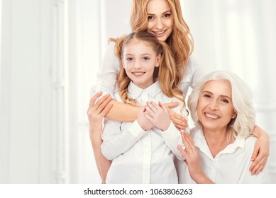 A Happy Family Is A Home. Family Portrait Of A Mature Woman Standing Embracing Her Adorable Daughter And Charming Mother While All Wearing Matching Attires And Posing For The Camera.