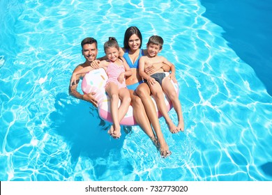 Happy family with inflatable ring relaxing in swimming pool
