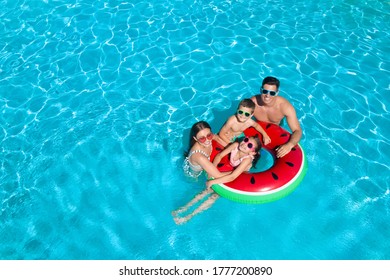 Happy family with inflatable ring in swimming pool, space for text. Summer vacation 