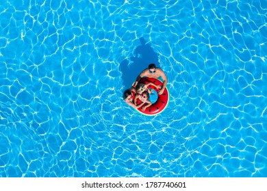 Happy Family With Inflatable Ring In Swimming Pool, Top View. Summer Vacation