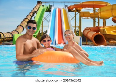Happy family with inflatable ring in swimming pool at water park