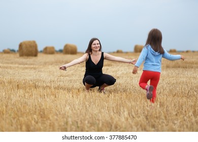 Happy Family. Joyful Mom And Her Little Daughter On A Field Of Hay And Straw Bales. Shallow Depth Of Field. Selective Focus On Mother.