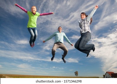 Happy family jumping in mid-air near house