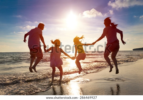 幸せな家族が一緒に海辺で飛び跳ぶ の写真素材 今すぐ編集