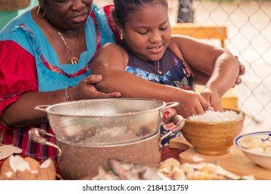 Happy Family In Kitchen. Black Mother And Little Grandaughter Preparing Lunch Together - Loving African American Mom Teaching Her Child Cooking, Enjoying Spending Time With The Girl.