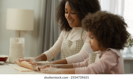 Happy family at kitchen cooking together smiling African American mom woman mother dirty face in white flour teaching cute kid daughter preschool child girl kneading dough with rolling pin cook fun - Powered by Shutterstock