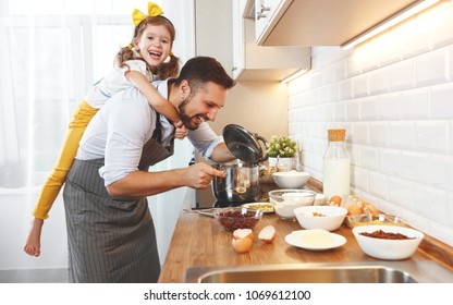 happy family in kitchen. Father and child daughter knead dough and bake the biscuits together - Shutterstock ID 1069612100