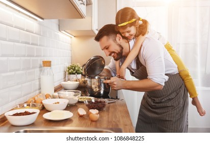 happy family in kitchen. Father and child daughter knead dough and bake the biscuits together