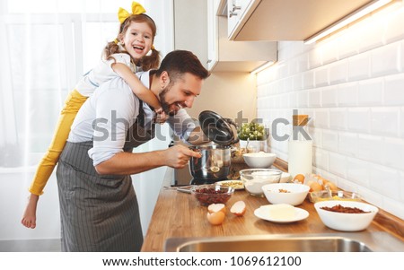 happy family in kitchen. Father and child daughter knead dough and bake the biscuits together