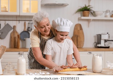 Happy family in kitchen. Grandmother and granddaughter child cook in kitchen together. Grandma teaching kid girl roll out dough bake cookies. Household teamwork helping family generations concept - Powered by Shutterstock