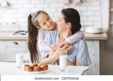 Happy family in kitchen. Loving daughter cuddling mom from back, grateful for her favorite muffins, copy space - Powered by Shutterstock