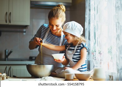 happy family in the kitchen. mother and  child daughter preparing the dough, bake cookies
