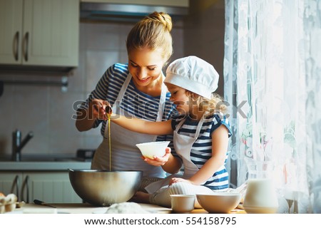 happy family in the kitchen. mother and  child daughter preparing the dough, bake cookies