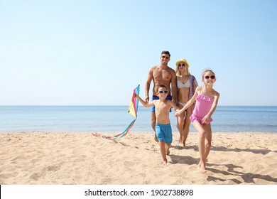 Happy family with kite at beach on sunny day
