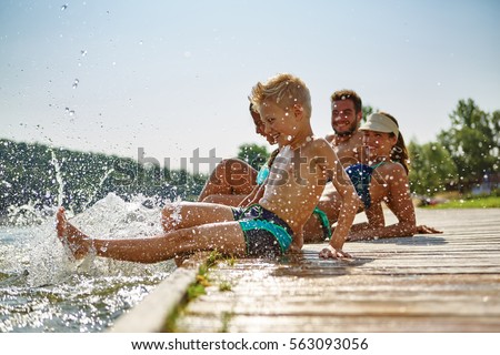 Happy family at a lake having fun and splashing water in summer