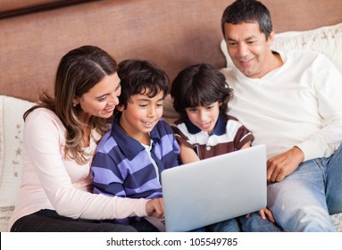 Happy Family With A Laptop Computer In Bed