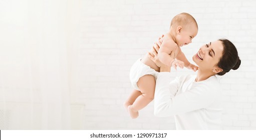 Happy family. Laughing mother lifting her adorable newborn baby son in air, panorama, copy space