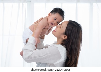 Happy family. Laughing mother lifting her adorable newborn baby son in air, copy space. asian mother lifting and playing with newborn baby, Health care family love together. Asian girl lifestyle.