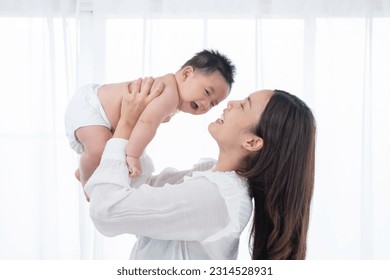 Happy family. Laughing mother lifting her adorable newborn baby son in air, copy space. asian mother lifting and playing with newborn baby, Health care family love together. Asian girl lifestyle. - Powered by Shutterstock