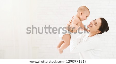 Happy family. Laughing mother lifting her adorable newborn baby son in air, panorama, copy space