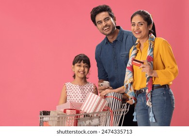 A HAPPY FAMILY LAUGHING TOGETHER WHILE STANDING WITH GIFTS TROLLEY
 - Powered by Shutterstock