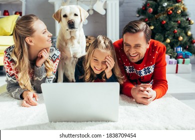 Happy Family Laughing While Watching Movie On Laptop Near Dog On Christmas