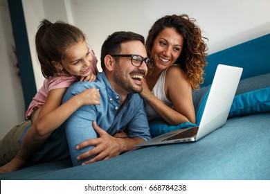 Happy family lies on bed and watching something on laptop.Laughing and fun. - Powered by Shutterstock