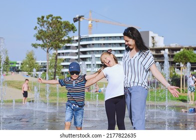 Happy Family Lifestyle And Holiday Concept. Mother, Little Boy, Girl Sitting, Walking In Old City, Street. Laughing On A Summer Sunny Day. Having Fun