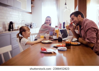 Happy family with little daughter eating breakfast together at home kitchen - Powered by Shutterstock