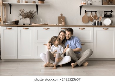 Happy family with little daughter sit on warm floor with underfloor heat system in modern home kitchen, enjoy time together, playtime and their good harmonic relations at new own or rented apartment - Powered by Shutterstock