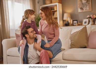 Happy family with little daughter sitting on sofa in living room - Powered by Shutterstock