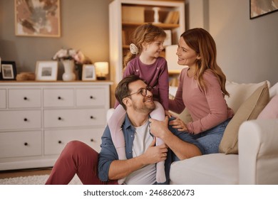 Happy family with little daughter sitting on sofa in living room  - Powered by Shutterstock