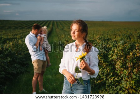 Happy family with little daughter spending time together in sunny field