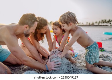 Happy family with little kids enjoying time at sea in exotic country, building sand castle. - Powered by Shutterstock