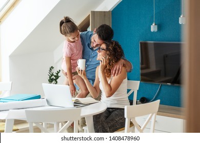 Happy family in living room. Mother works from home ,while her husband and daughter support her . - Powered by Shutterstock