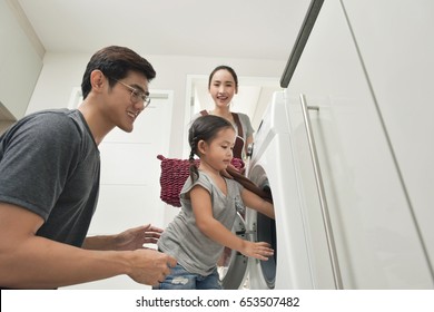 Happy Family Loading Clothes Into Washing Machine In Home