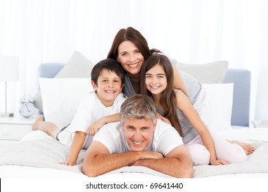 Happy Family Looking At The Camera On Their Bed