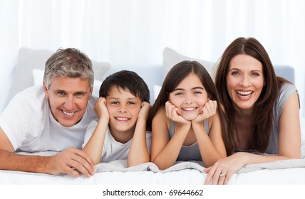 Happy Family Looking At The Camera On Their Bed