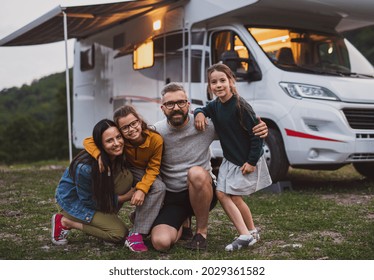 Happy Family Looking At Camera Outdoors At Dusk, Caravan Holiday Trip.