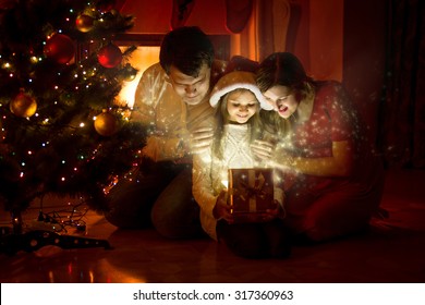 Happy Family Looking Inside Of Magic Christmas Gift Box 