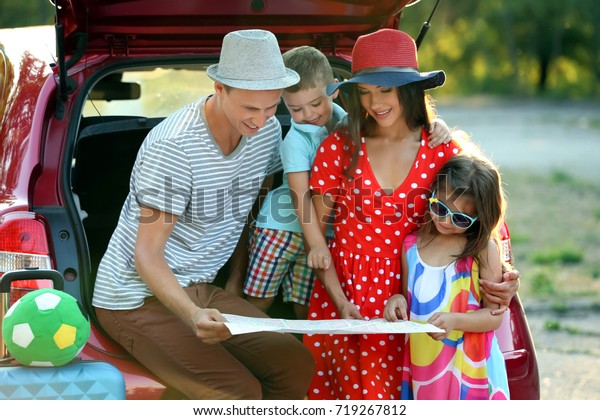 Happy\
family looking at map next to car in\
countryside