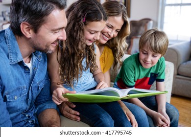 Happy Family Looking At A Photo Album At Home