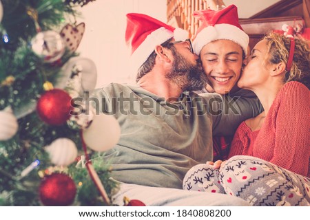 Happy family in love celebrate christmas eve all together with kiss and hug and joy - joyful people with red winter decorations at home - concept of father and mother and son together