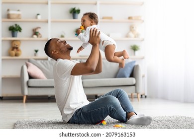 Happy Family. Loving Black Dad Lifting His Adorable Infant Baby In Air, Caring Young African American Father Bonding With Cute Toddler Child At Home, Enjoying Spending Time Together, Copy Space